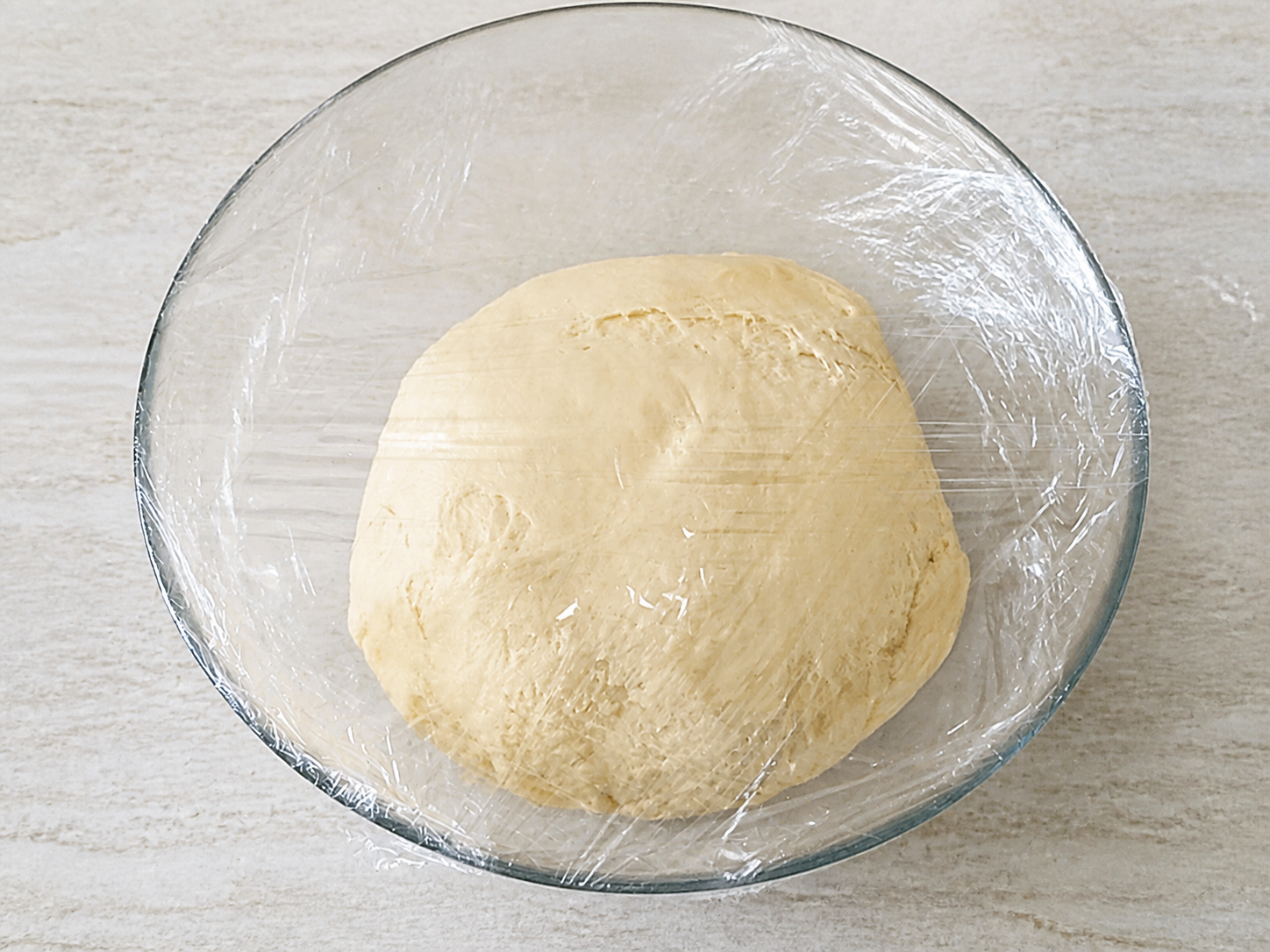 Apple pie dough resting covered in a glass bowl